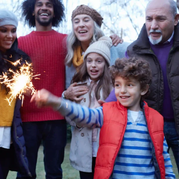 young boy holding sparklers in the family garden enjoying bonfire night
